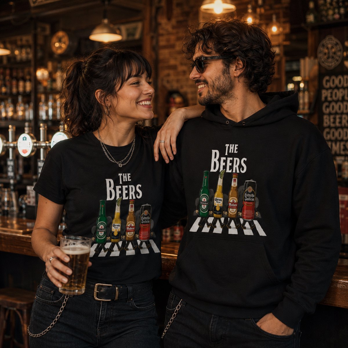 Pareja con camiseta y sudadera negras The Beers, parodia Abbey Road con cervezas